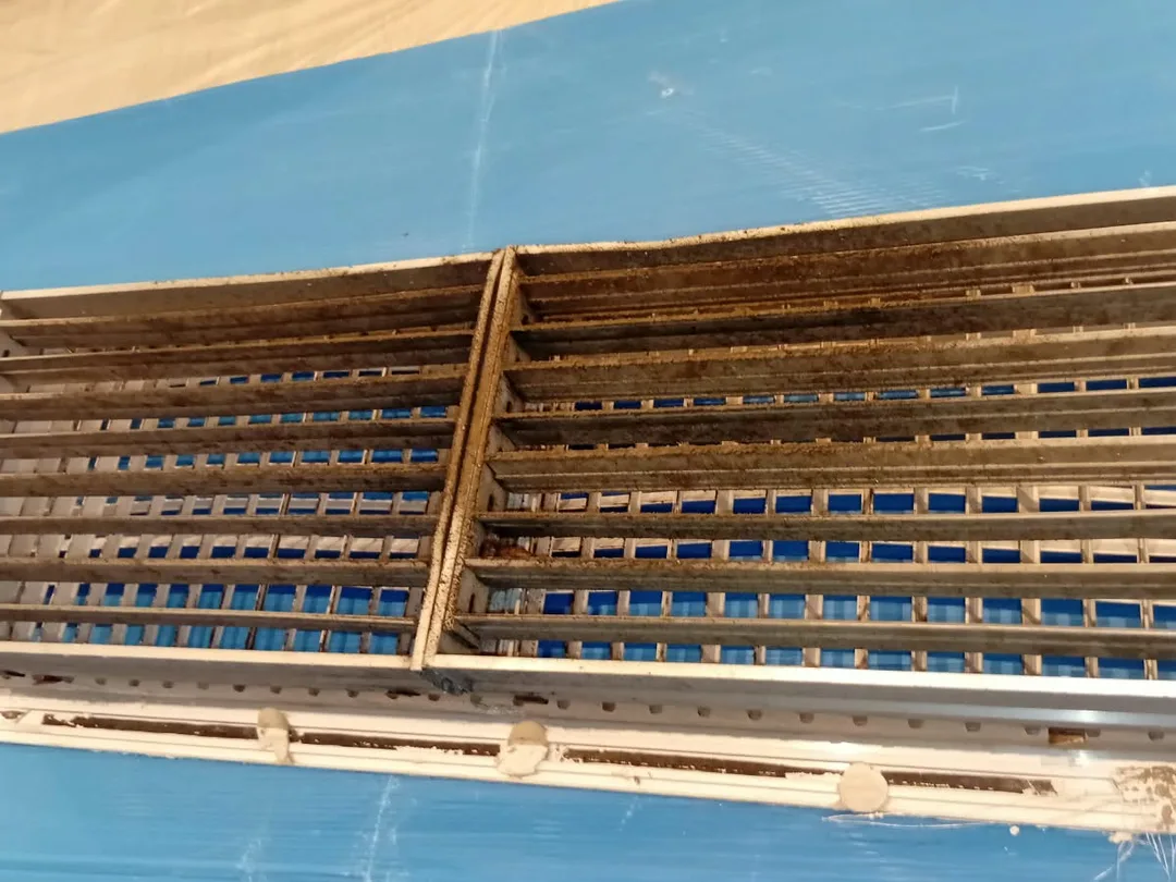 Before cleaning: a ceiling linear grille in a Dubai apartment, the gaps between its blades packed with grey dust.