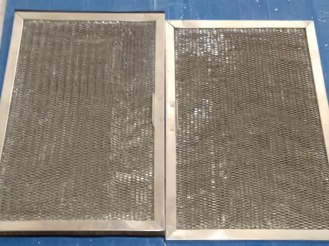 Before cleaning: two aluminium mesh AC filters clogged with grey dust.