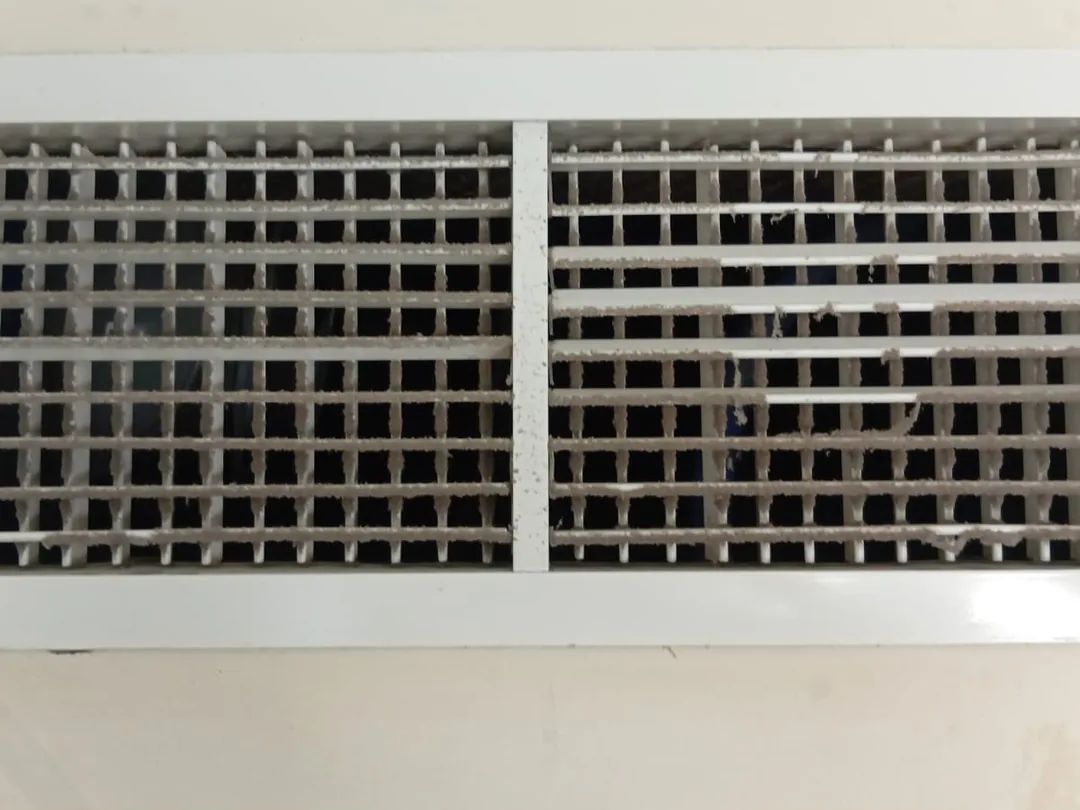 Before cleaning: a wall supply grille with its egg-crate core darkened by trapped dust.