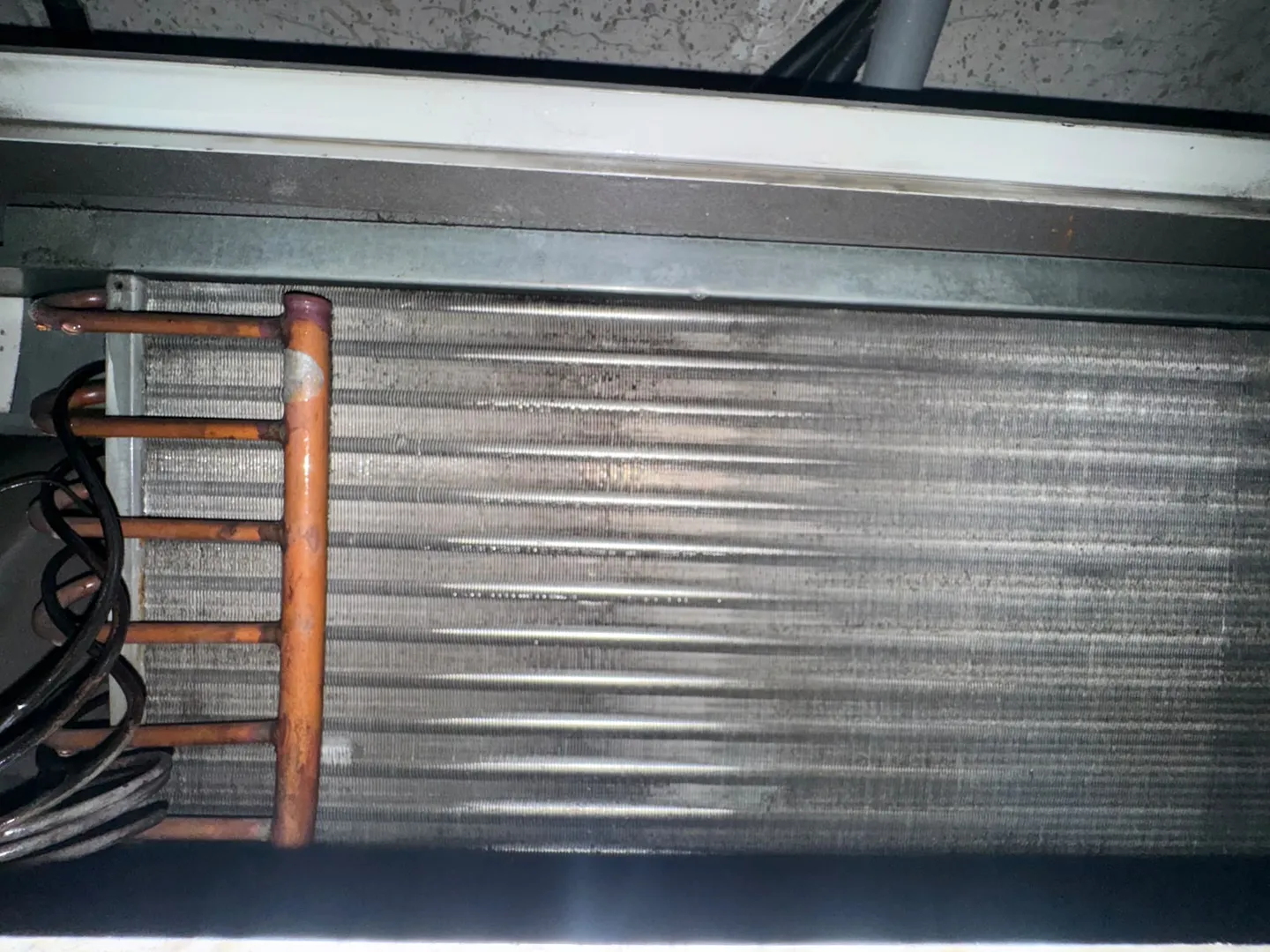 An AC evaporator coil after cleaning, its aluminium fins and copper pipework clear of built-up dust.