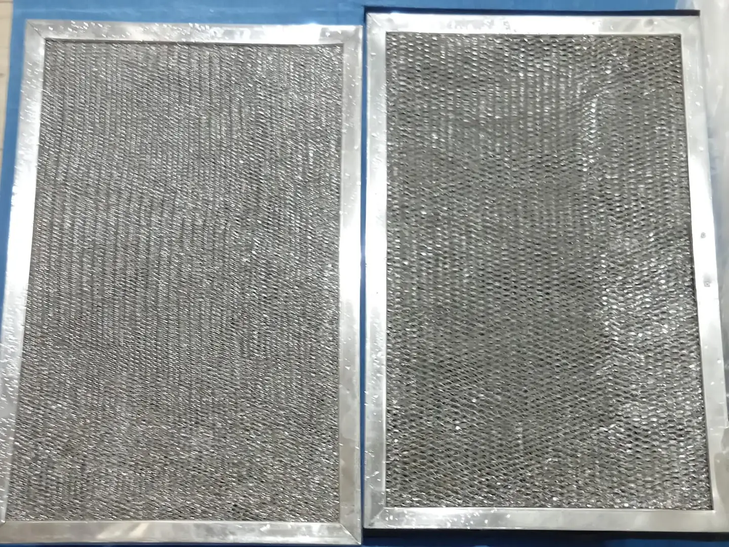 Two metal mesh AC filters after washing, laid out side by side and clear of dust.