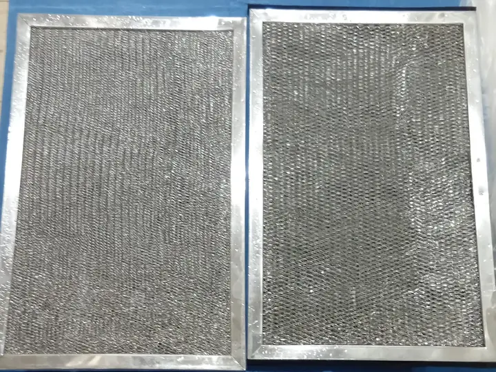 Two metal mesh AC filters after washing, laid out side by side and clear of dust.