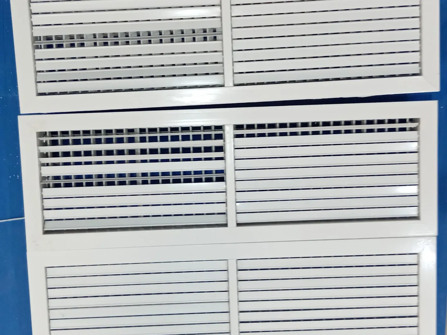 Three white AC grilles after cleaning and sanitising, their louvres spotless and free of mould.