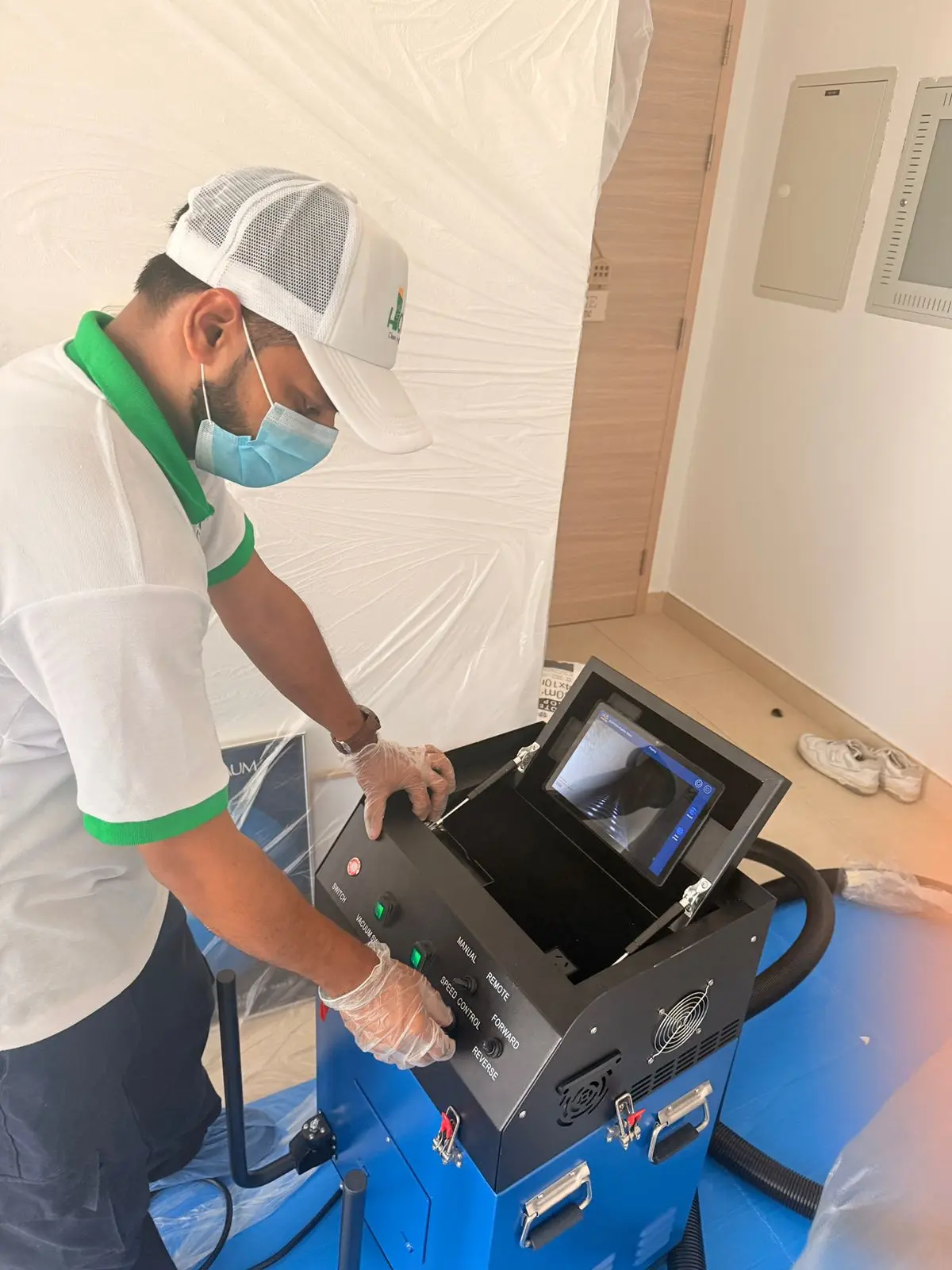 A Homezy technician at the roto-brush machine's controls, its built-in monitor showing the live camera view from inside a duct.
