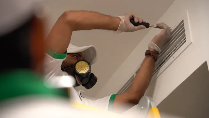 A Homezy technician checking an indoor AC unit on a scheduled maintenance visit.